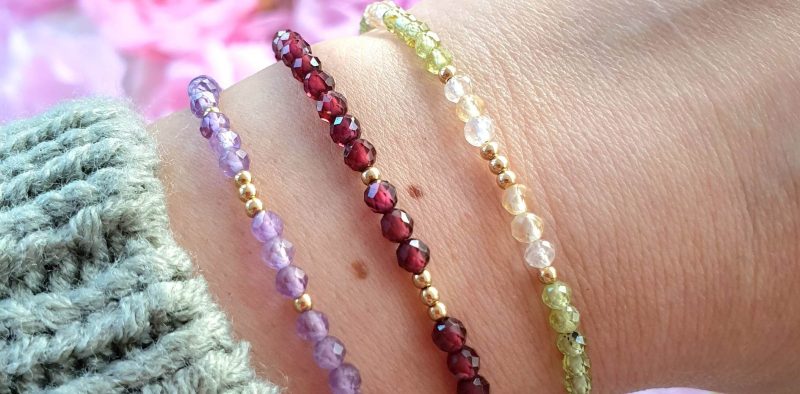 Woman’s wrist wearing multiple dainty crystal bracelets – natural gemstone stacking jewellery for energy, style, and intention.